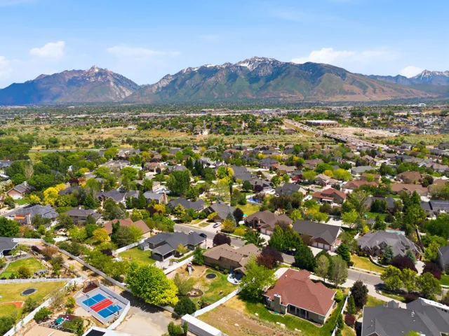 Expansive aerial showcasing a residential neighborhood with mature trees and mountain scenery