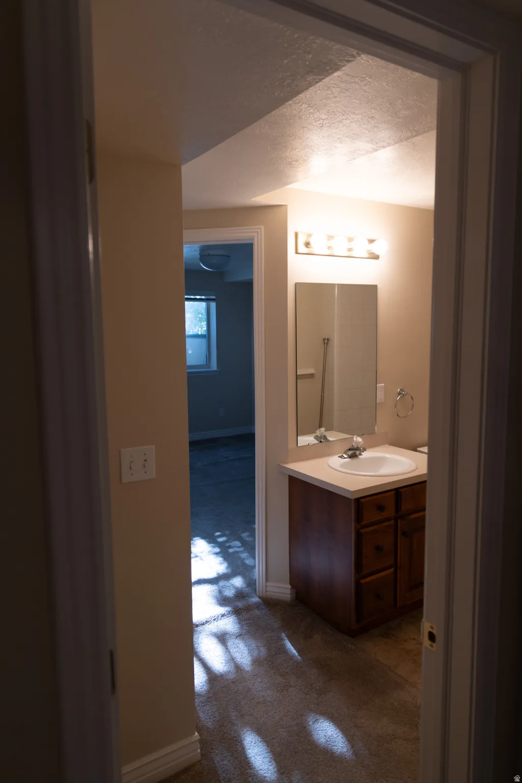 Bathroom vanity with a light countertop, integrated sink, and wood-finish cabinetry