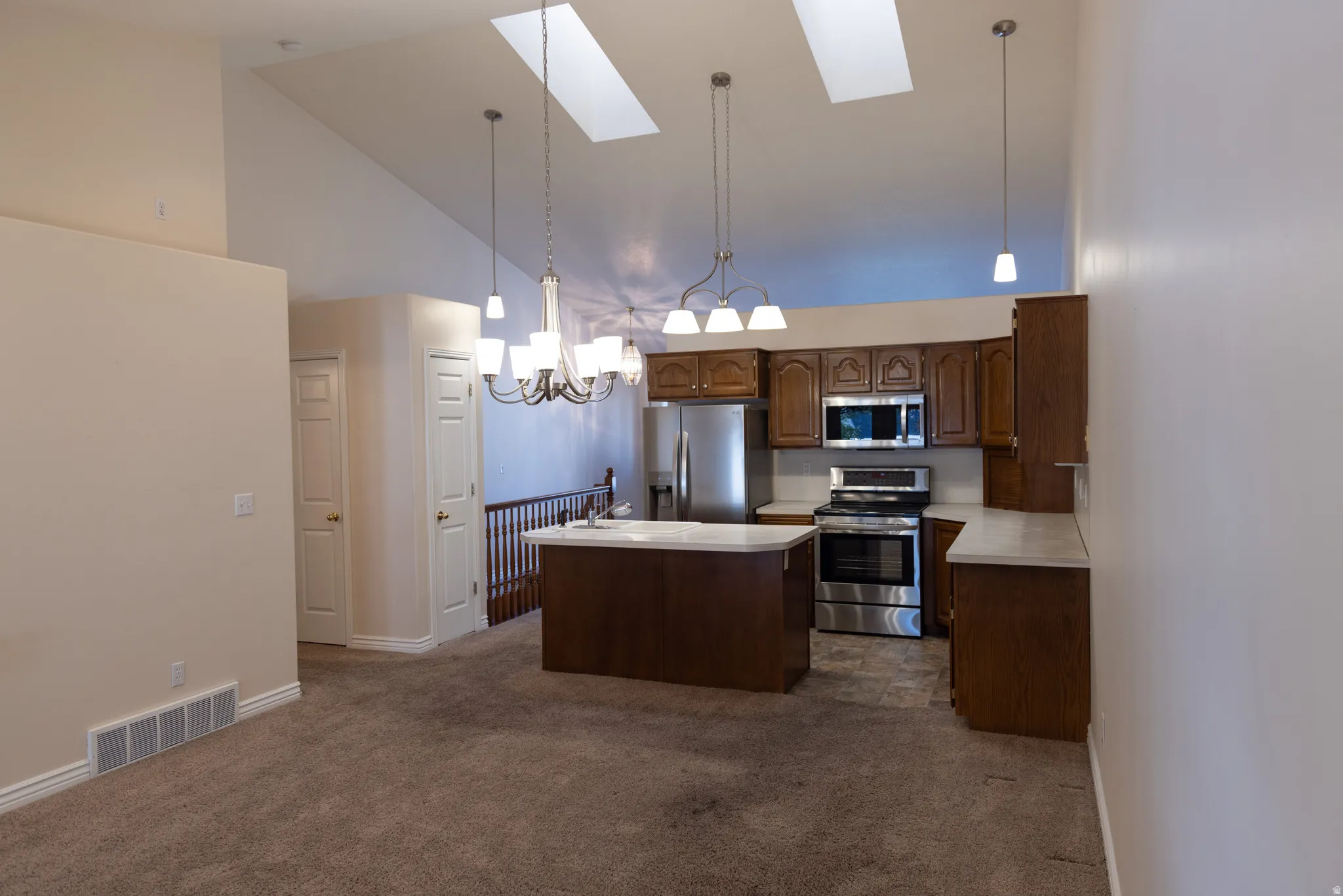 Kitchen featuring dark wood cabinetry, stainless steel appliances, and a central island with a light-colored countertop