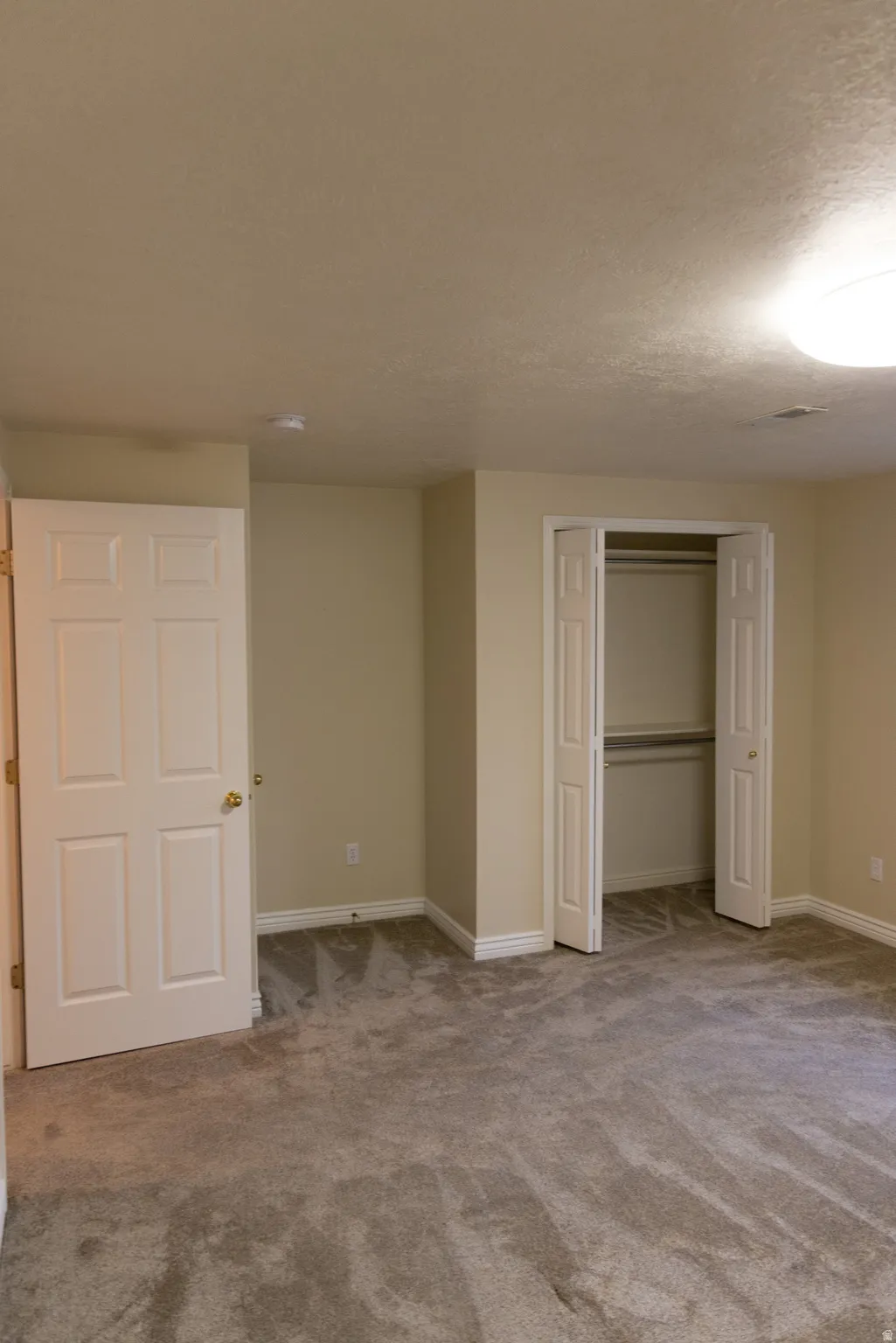 Wall-to-wall carpeting in a neutral tone, white baseboards, and light-colored walls