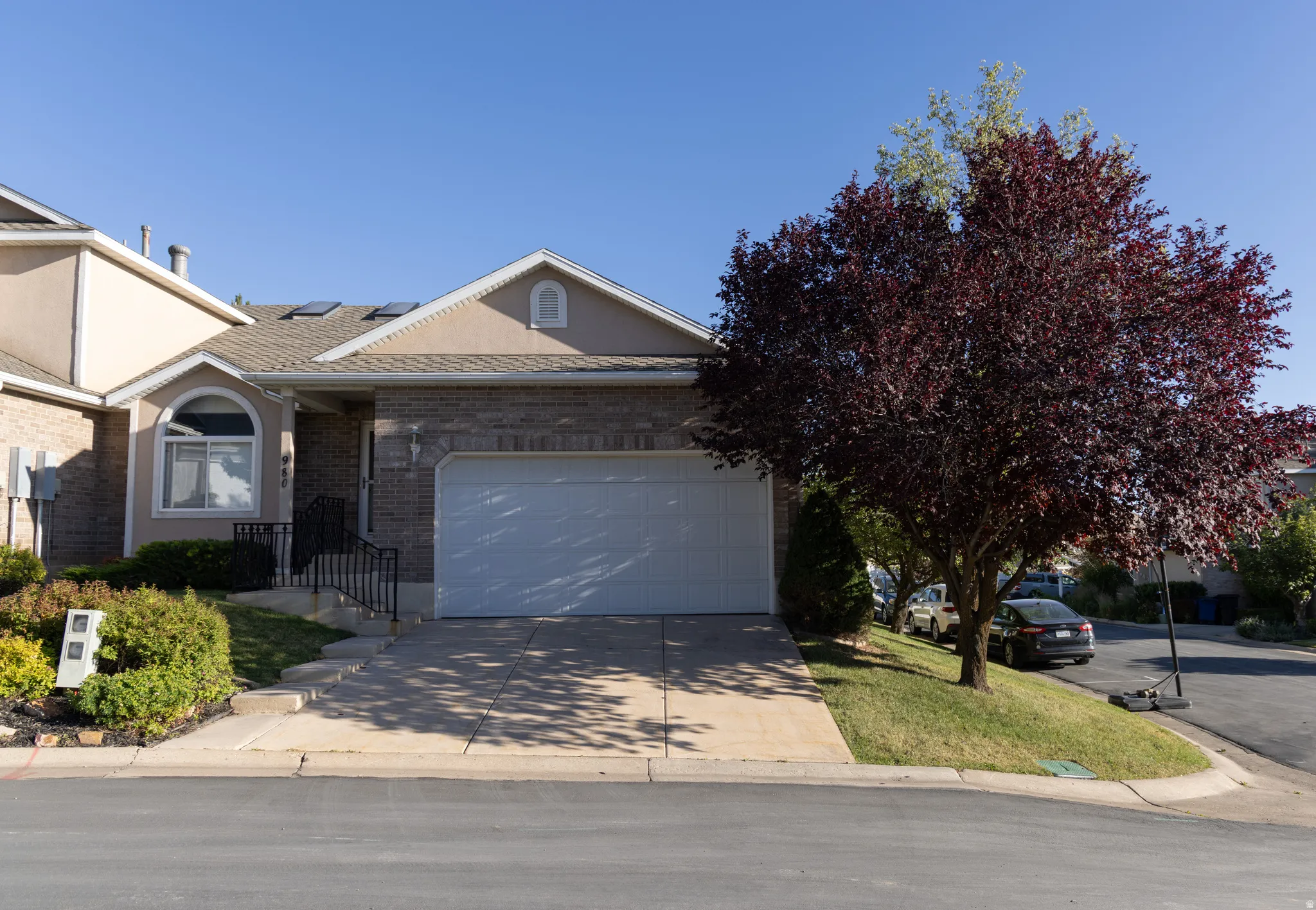 Front exterior with a two-car garage, brick and stucco facade, concrete driveway, and front landscaping