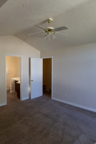 Spacious room with vaulted ceilings and textured walls, featuring a ceiling fan with integrated lighting