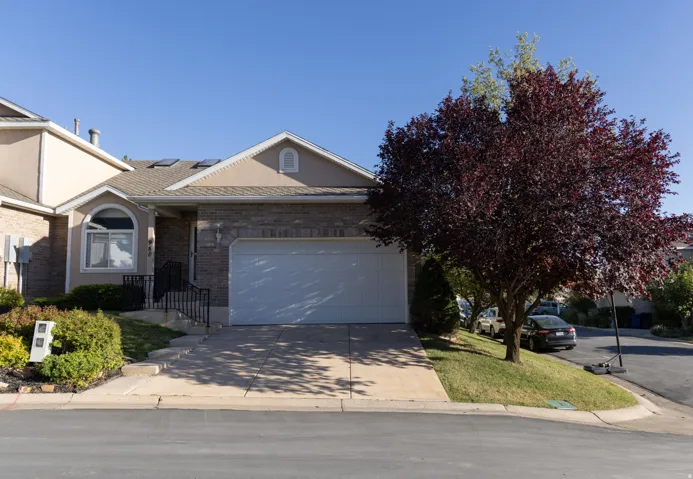 Front exterior with a two-car garage, brick and stucco facade, concrete driveway, and front landscaping