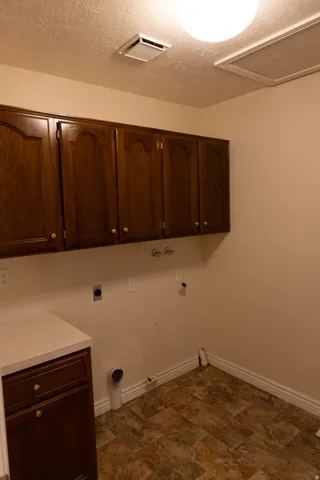 Laundry area featuring wood-finish cabinetry, a light-toned countertop, and patterned floor tiles