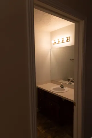 Bathroom vanity featuring a light-toned countertop with integrated sink, a dark wood-finish cabinet, a large wall-mounted mirror, and a four-bulb vanity light fixture