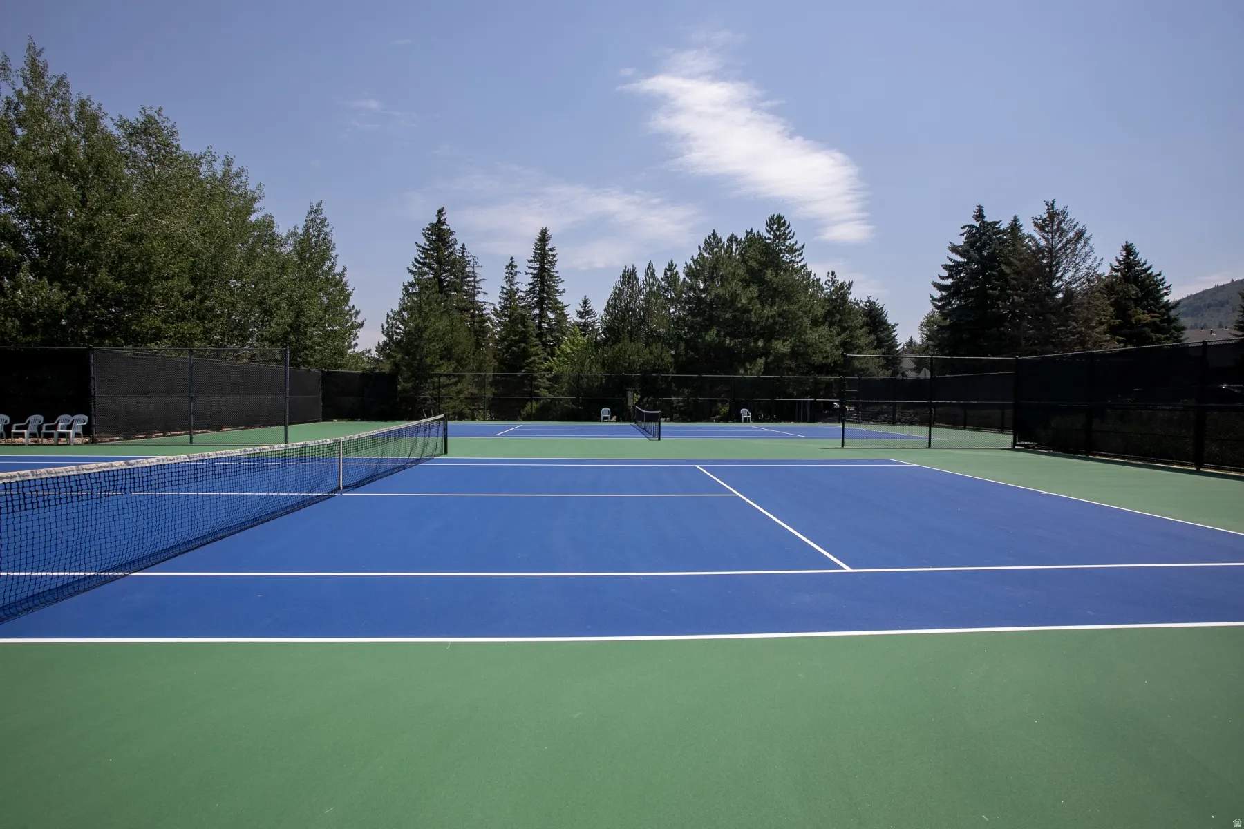 Dual tennis courts with blue and green surfacing, defined by white court lines