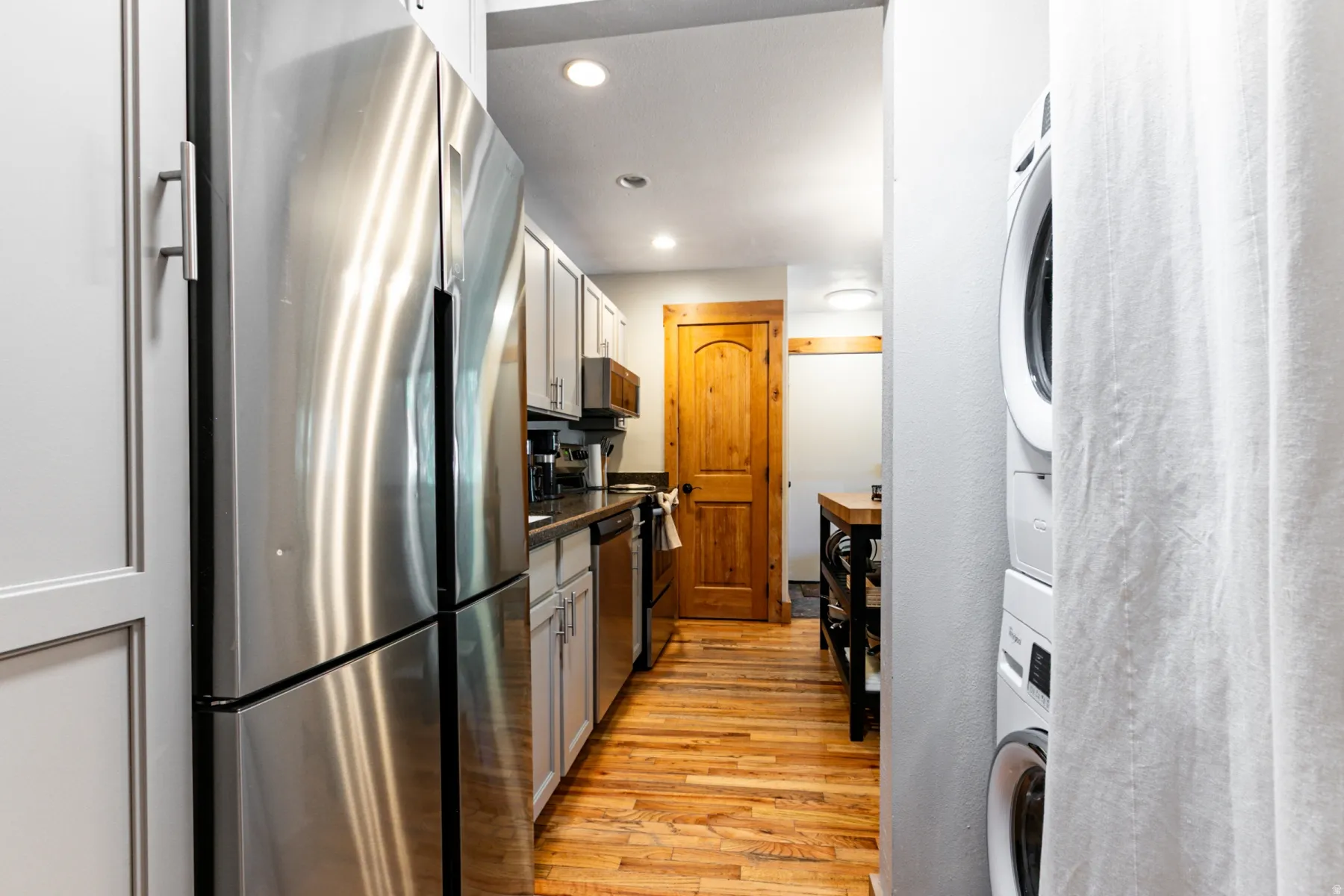 Kitchenette featuring stainless steel appliances, light-toned cabinetry with coordinating hardware, a built-in dishwasher, recessed lighting, and wood-finish flooring