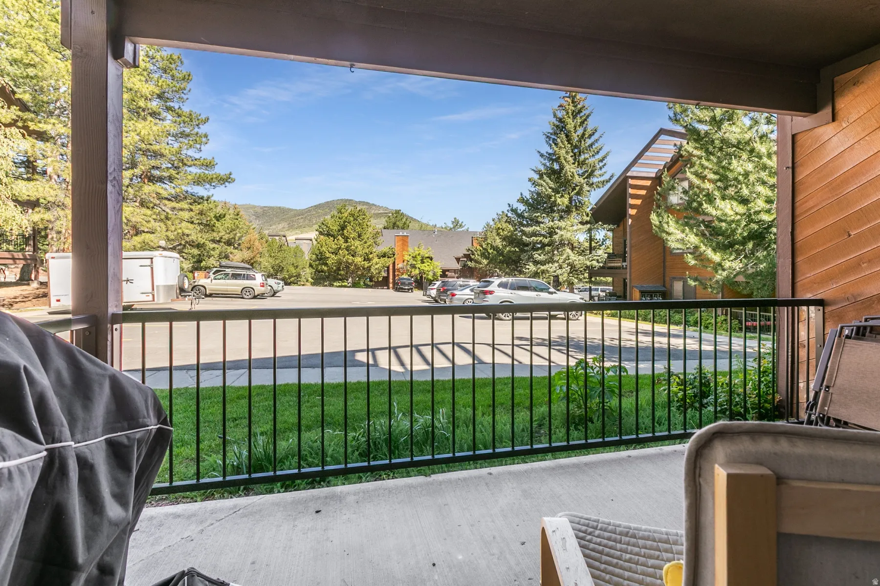 Private patio with concrete flooring, black metal railing, and wood support beams