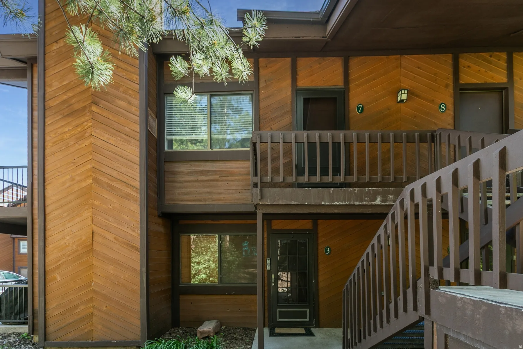 Exterior featuring horizontal and chevron wood paneling, dark trim, and multiple entry doors