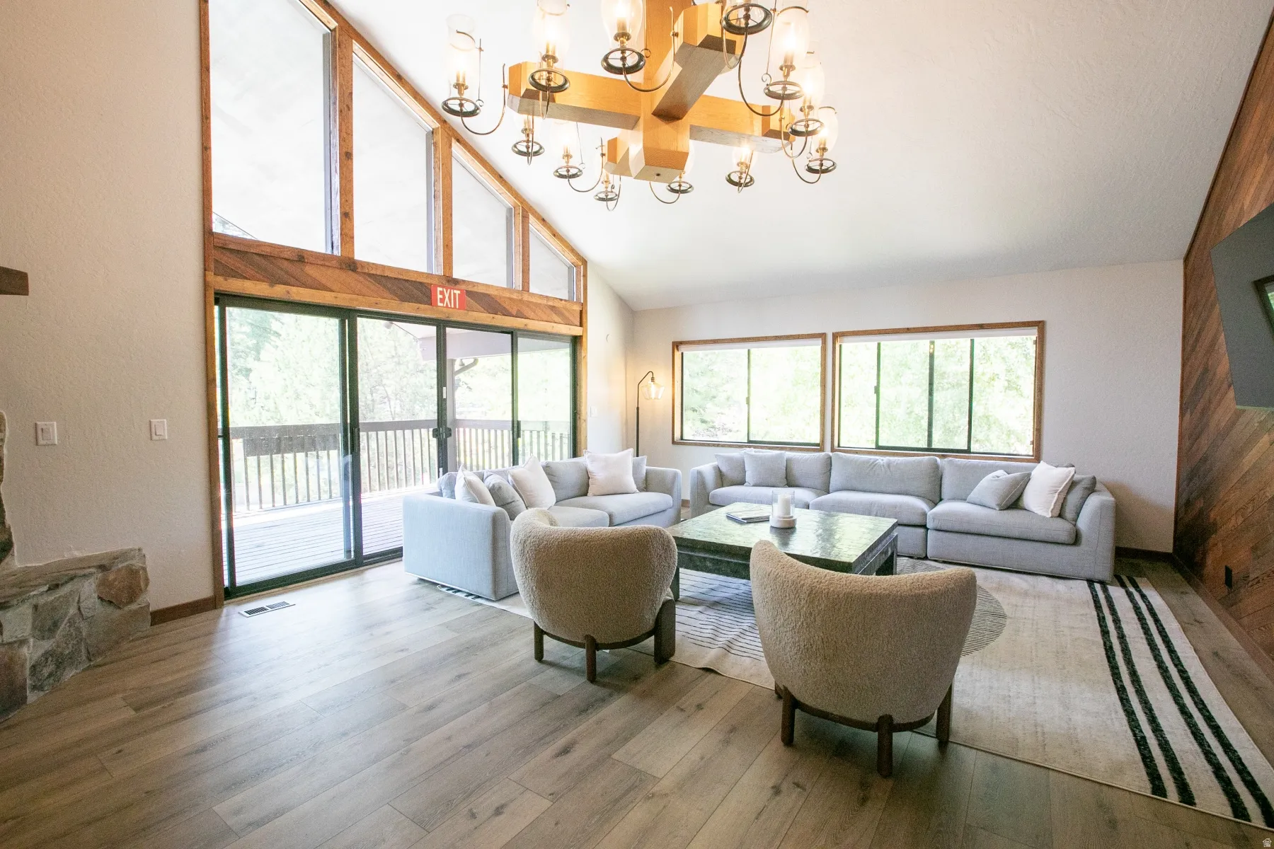 Living area featuring a vaulted ceiling with exposed wood beam, a large multi-light chandelier, and wood-finish flooring