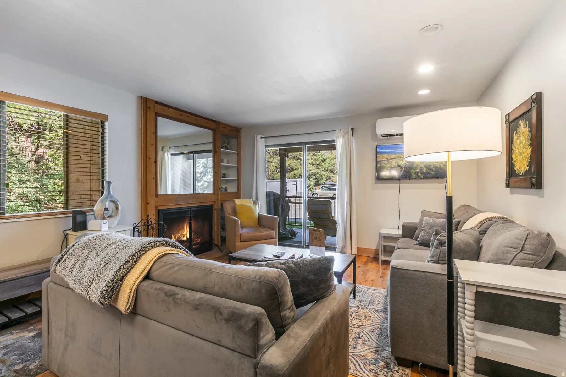 Open living area featuring wood-finish flooring, a wood-surround fireplace with a large integrated mirror, and built-in shelving