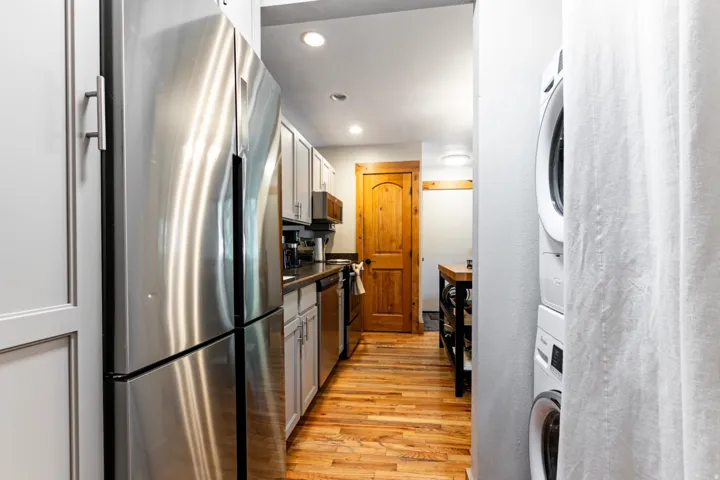 Kitchenette featuring stainless steel appliances, light-toned cabinetry with coordinating hardware, a built-in dishwasher, recessed lighting, and wood-finish flooring