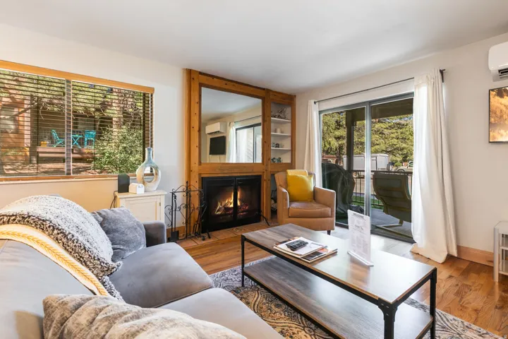 Living area featuring wood-finish flooring, a wood-surround fireplace with a metal grate, and a large mirror