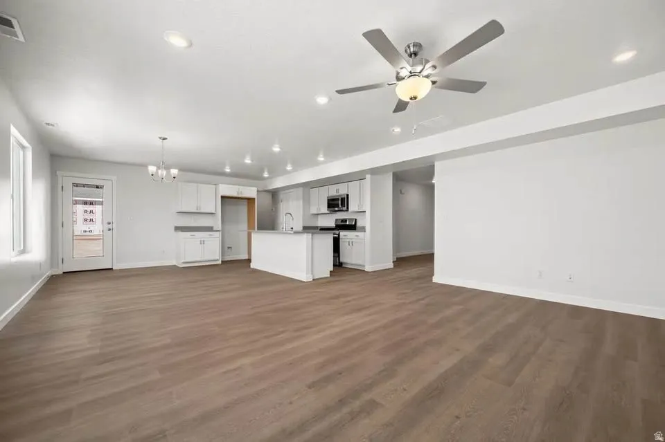 Expansive open-concept living space featuring wood-finish flooring, recessed lighting, and a contemporary ceiling fan