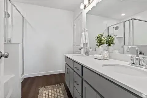 Bathroom featuring a dual vanity with light gray cabinetry, white countertops, two integrated sinks, and polished chrome fixtures