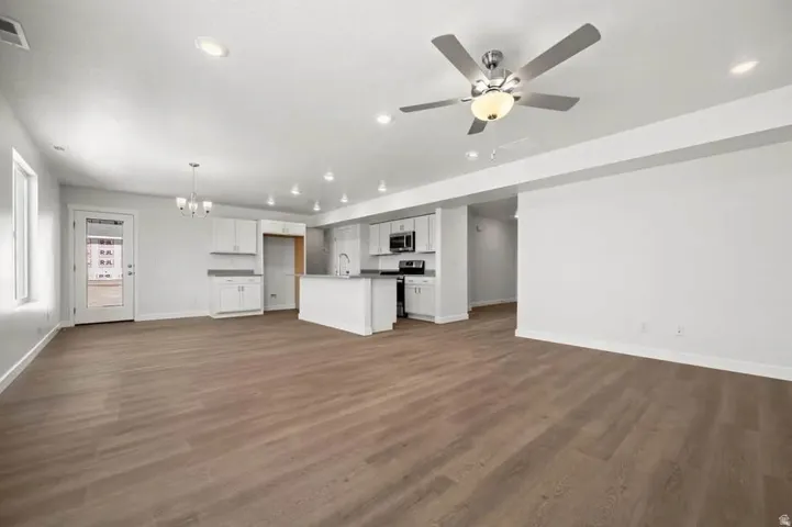 Expansive open-concept living space featuring wood-finish flooring, recessed lighting, and a contemporary ceiling fan