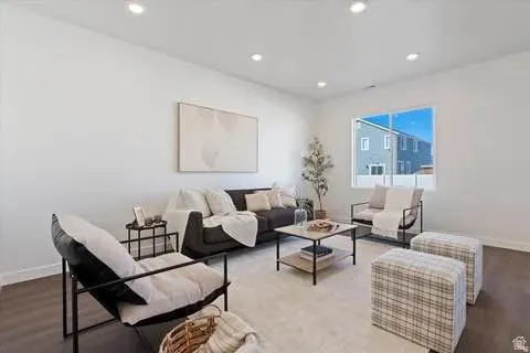 Bright living area featuring recessed lighting, a large window, white walls, and wood-finish flooring