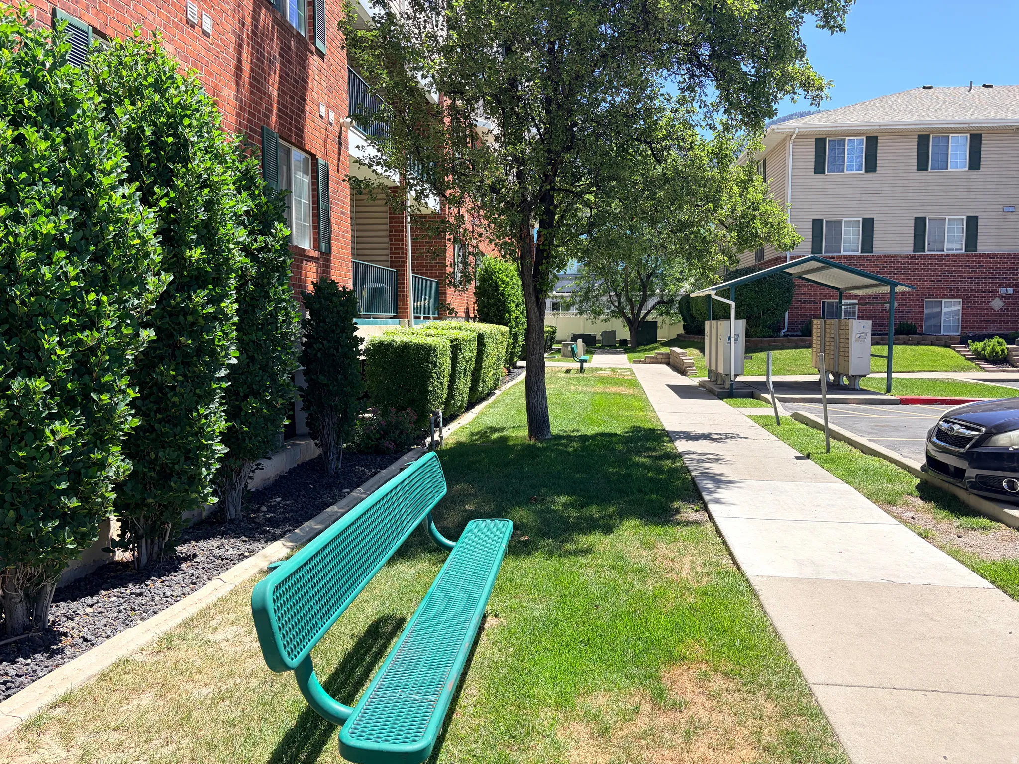 Manicured green spaces featuring mature trees and shrubs, bordered by a concrete walkway