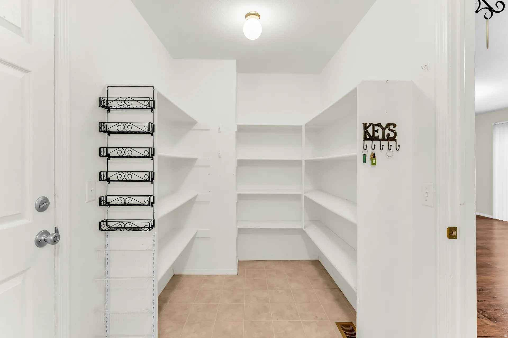 Spacious pantry featuring extensive built-in shelving, ceiling-mounted light fixture, and tiled flooring