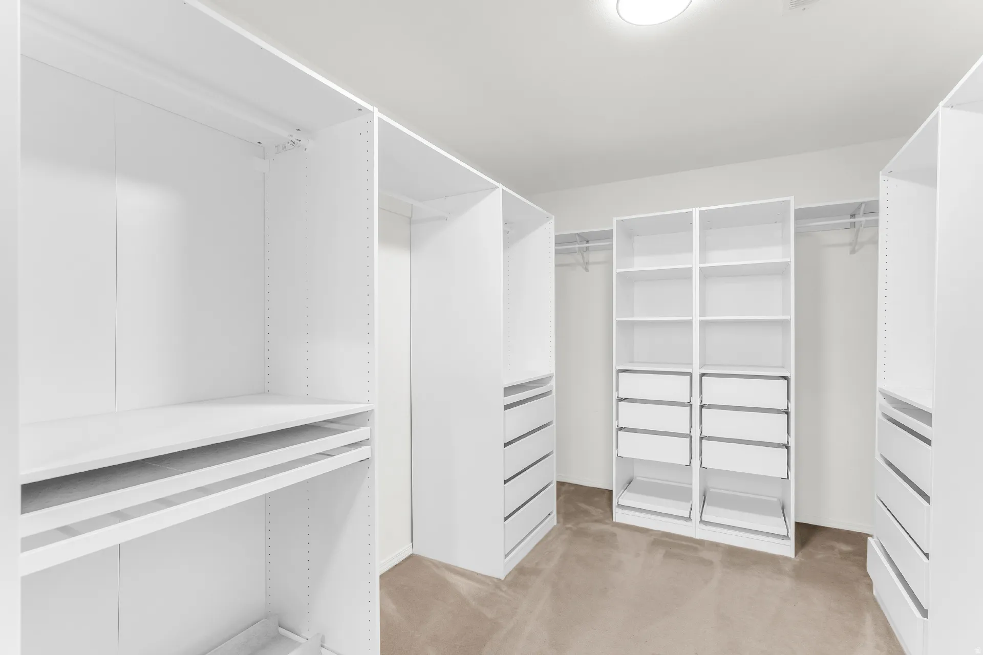 White built-in cabinetry with adjustable shelving, integrated drawers, and ample hanging rods