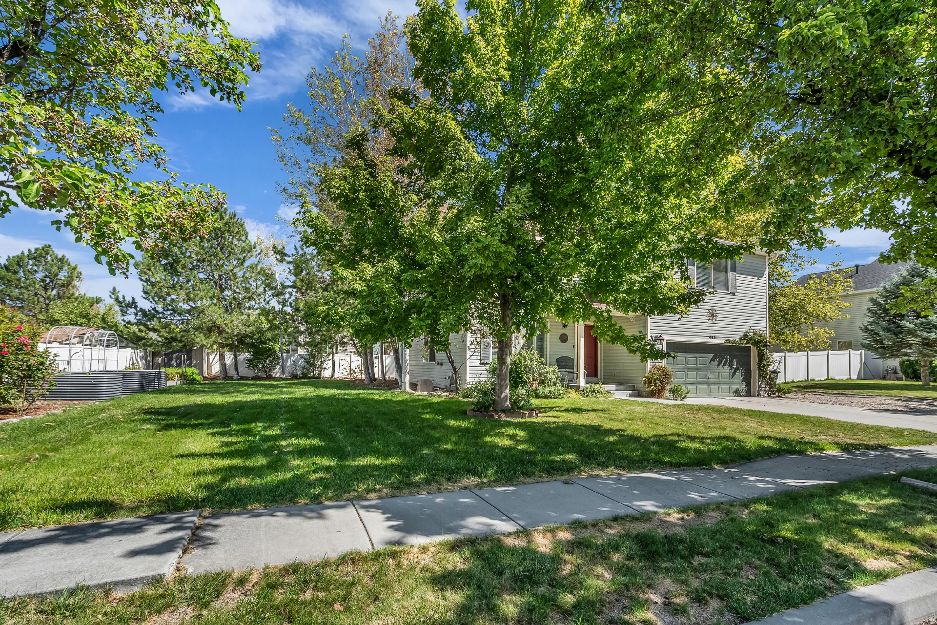 Two-story residence with siding exterior, mature trees, an attached garage, and a concrete driveway