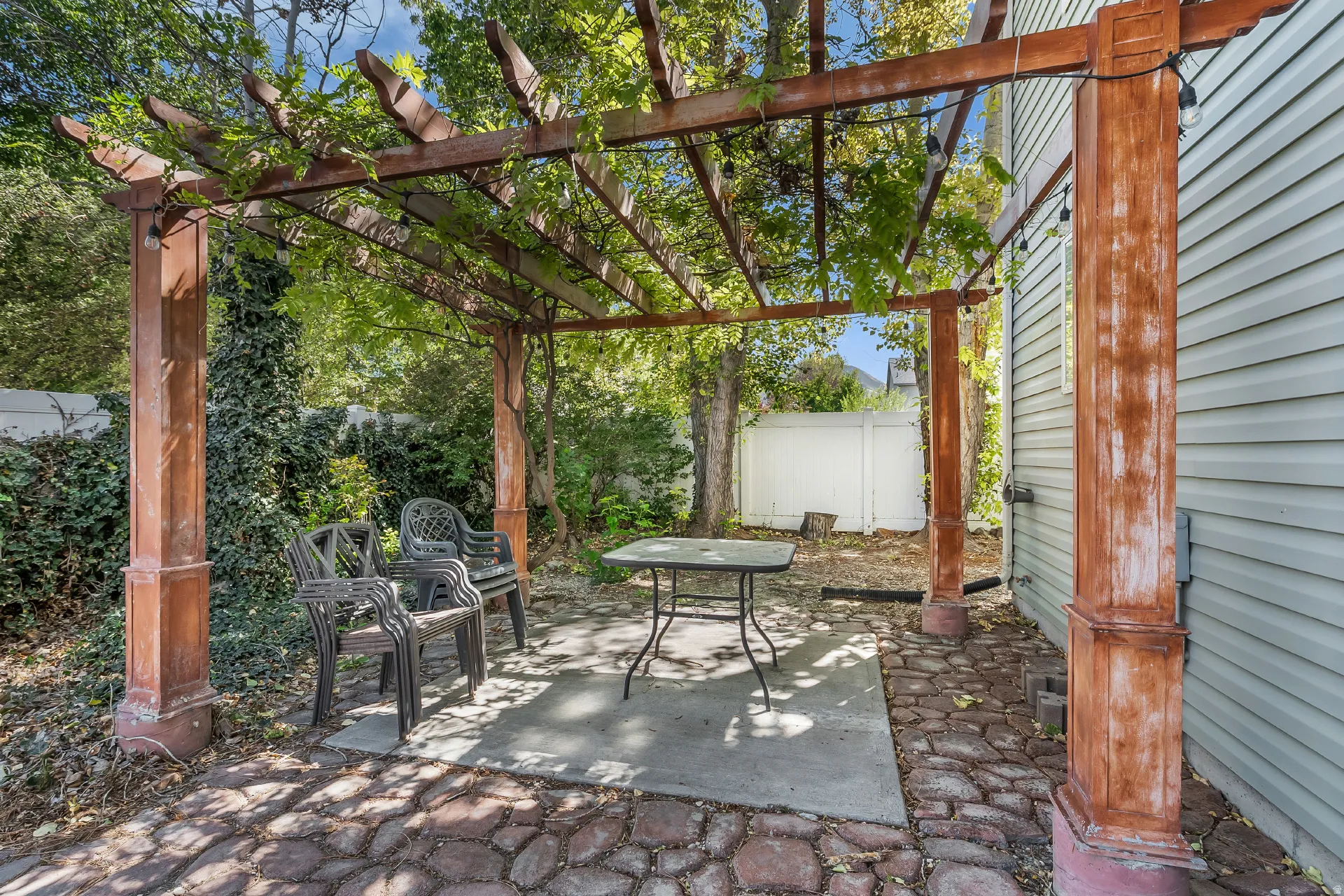 Patio with a wooden pergola, concrete pad, and stone-finish paving