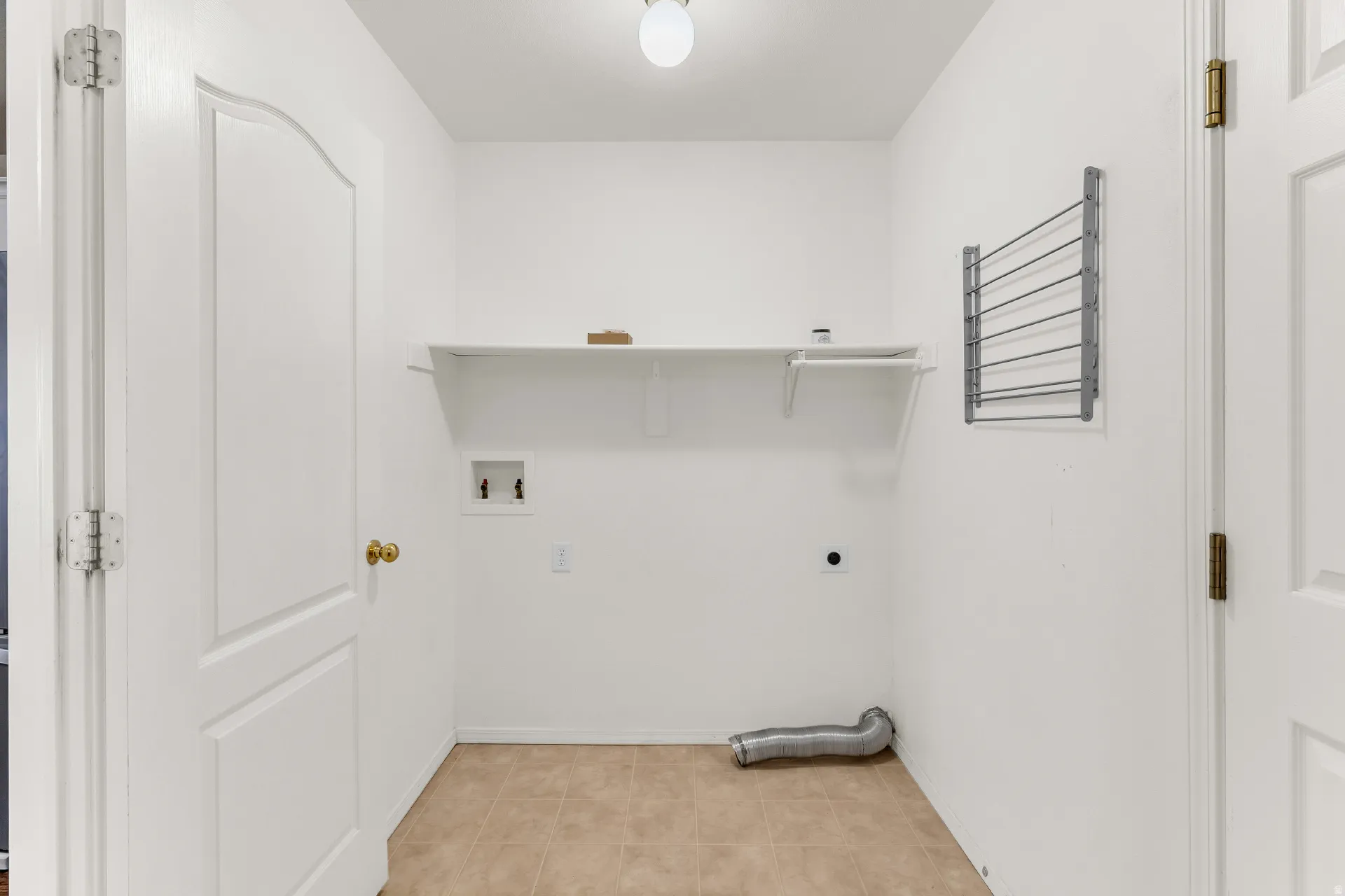 Utility room featuring tile flooring, a wall-mounted drying rack, and built-in shelving