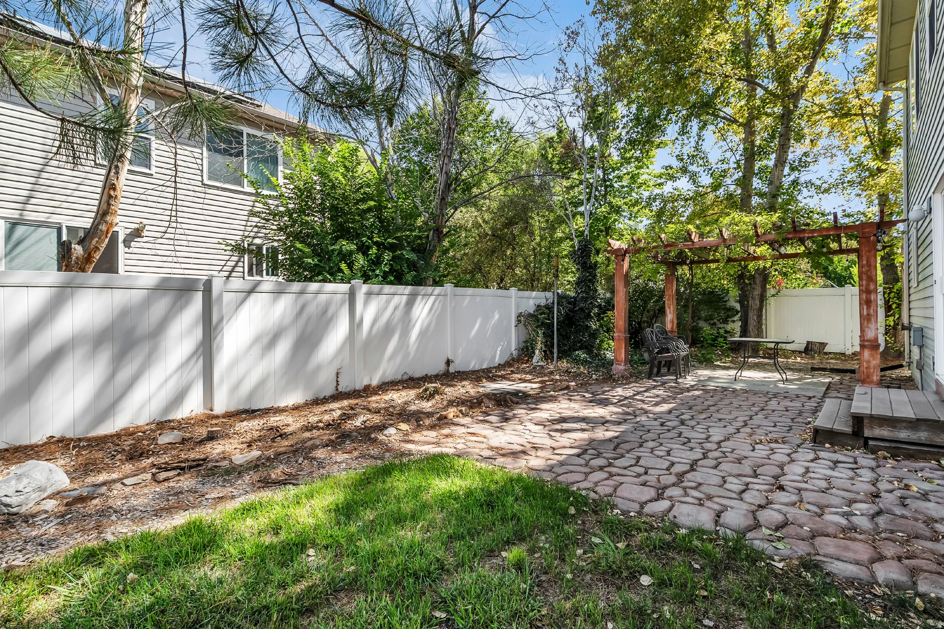 Private fenced yard featuring a stone paver patio and a wood pergola