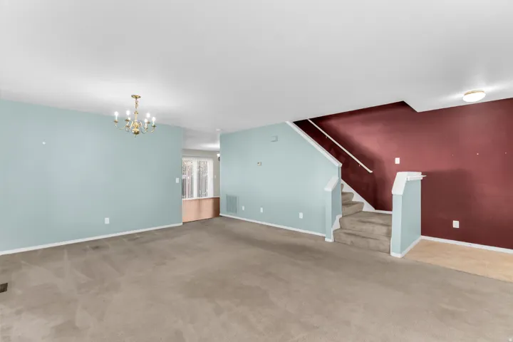 Spacious living area featuring neutral carpeting and a brass-finish chandelier
