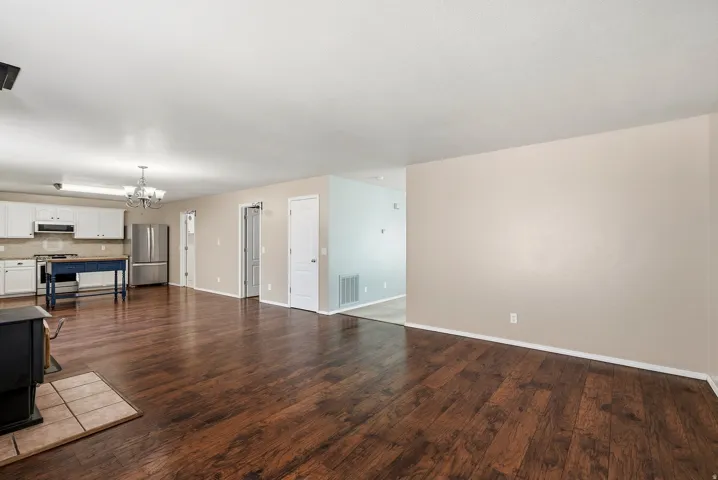 Expansive open-concept living area featuring wood-finish flooring, a kitchen with white cabinetry, and stainless steel appliances