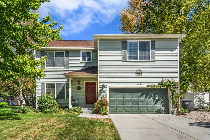Two-story property featuring light-colored siding, a covered entryway, a red entry door, a multi-pane garage door, and a concrete driveway