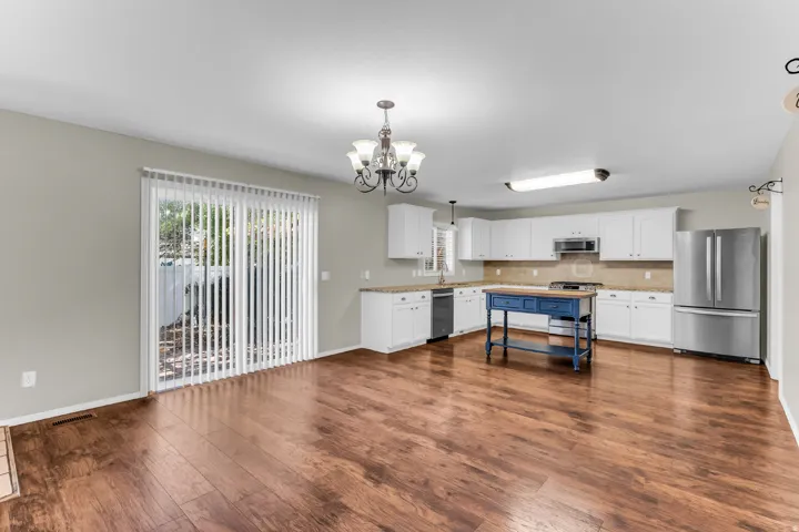 Open-concept kitchen with white cabinetry, stainless steel appliances, and a central blue island
