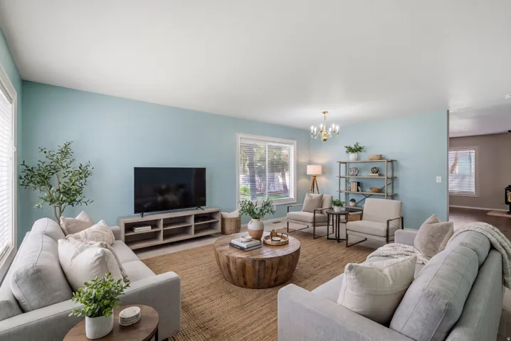 Spacious living area featuring light blue walls, multiple large windows, and a brass chandelier