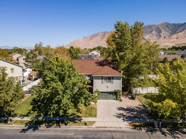 Two-story residence with a brown shingle roof, light green siding, and an attached garage