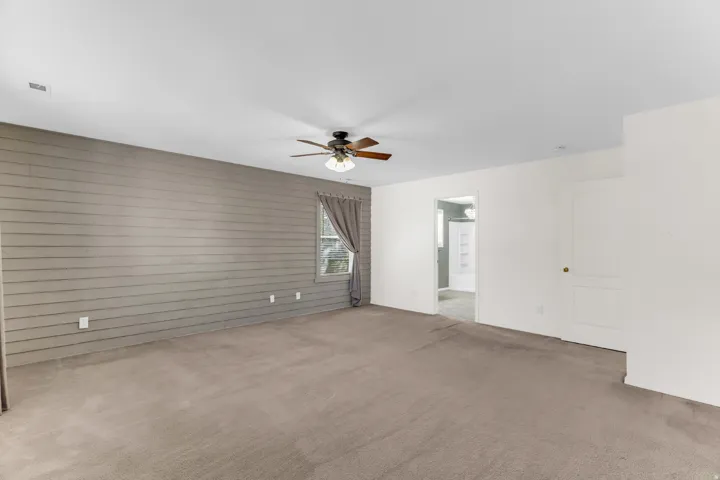 Expansive room with neutral carpet flooring and a wood-paneled accent wall