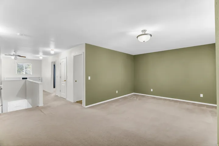 Carpeted upper-level space featuring a contemporary ceiling fan, flush-mount lighting, and a window with natural light