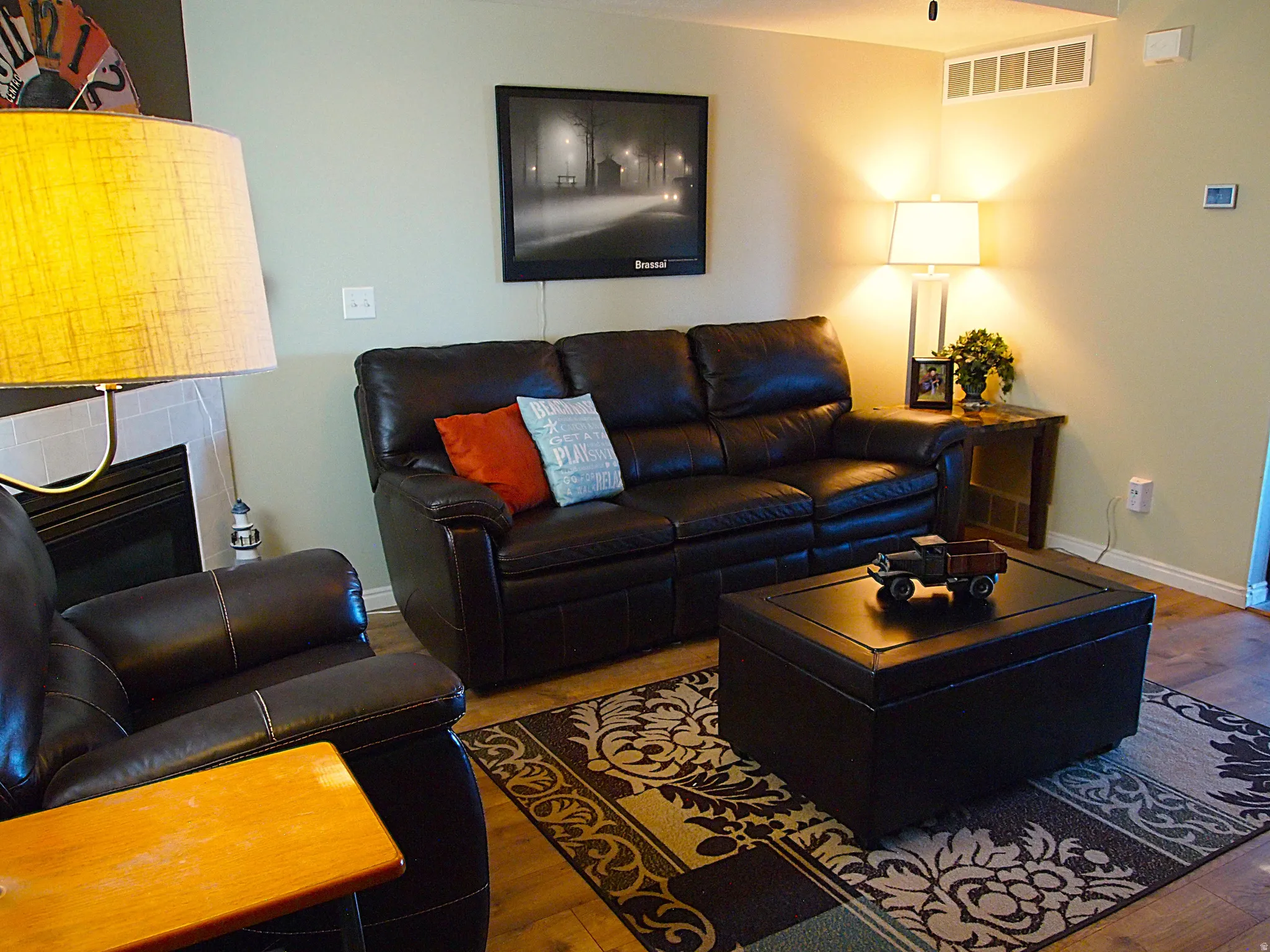 Living area featuring wood-finish flooring, a contemporary area rug, and a built-in fireplace with a tile surround