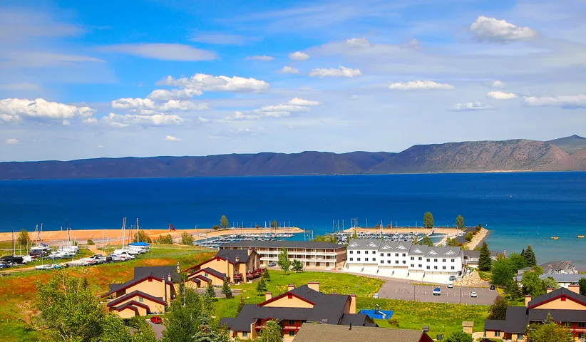 Expansive waterfront setting featuring a marina, distant mountains, and multiple residential structures