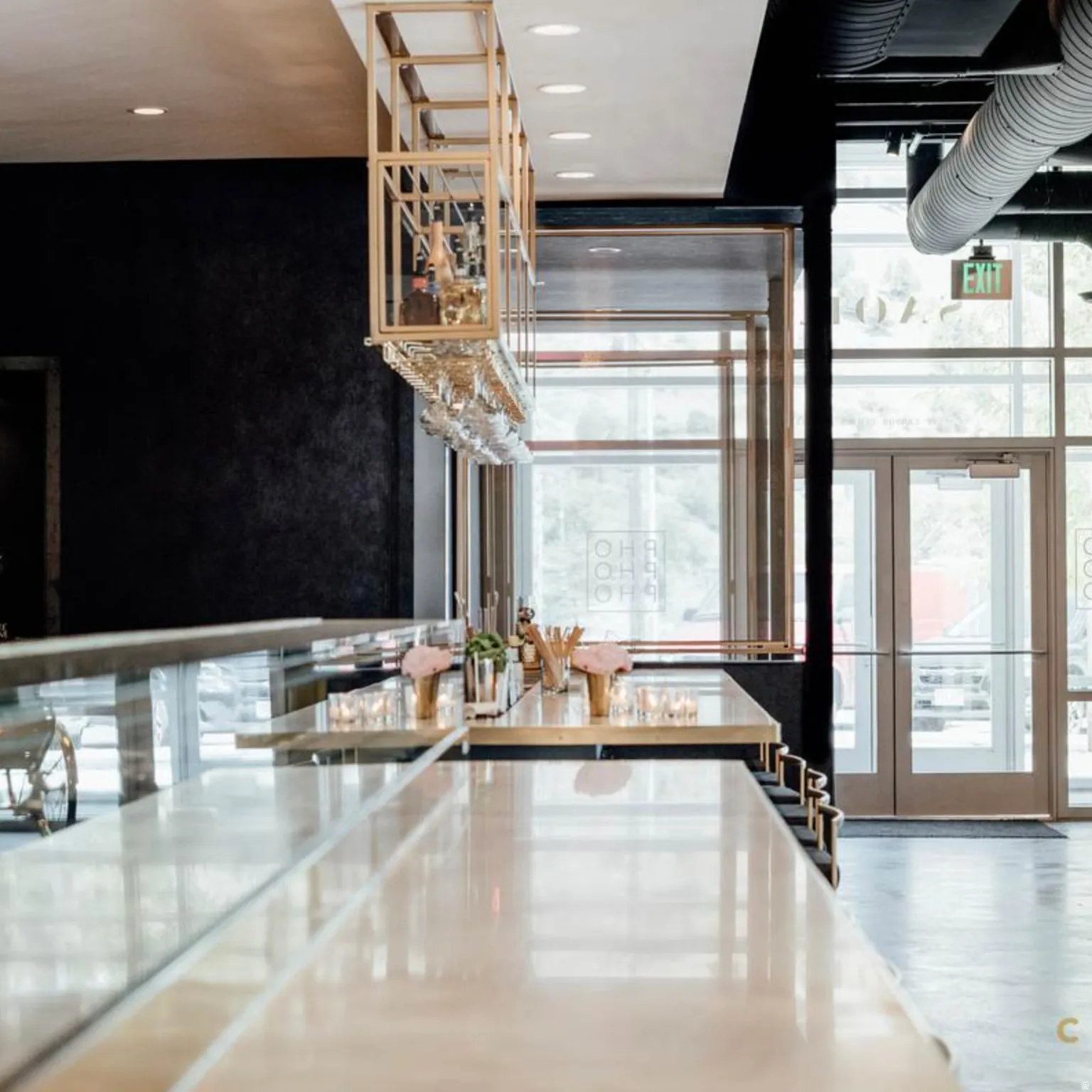 Contemporary bar area featuring a polished countertop, an overhead brass-finish wine glass rack, and recessed ceiling lighting