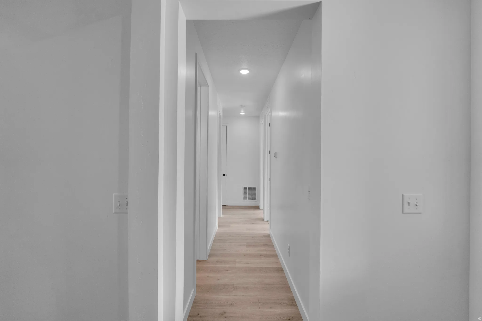 Corridor featuring wood-finish flooring, recessed lighting, white walls, and white trim