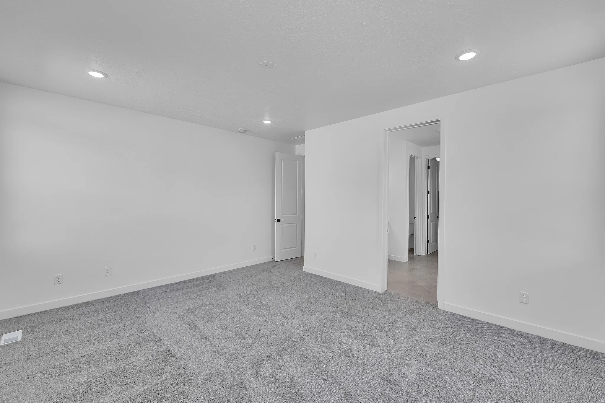 Spacious room featuring neutral gray carpeting and recessed lighting