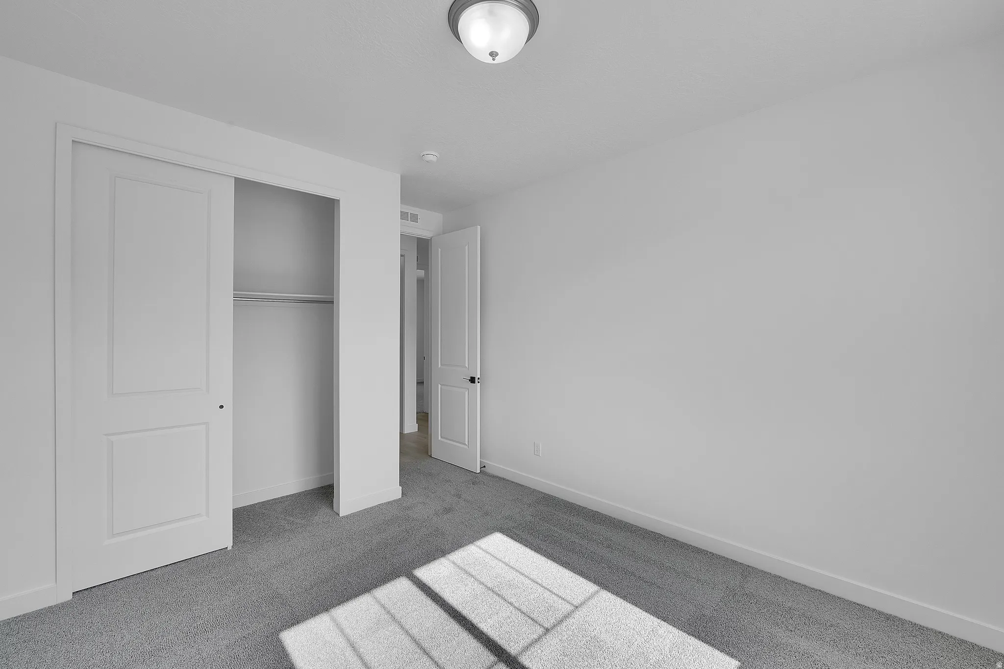 Carpeted room featuring a double-door closet with shelving and hanging rod, white walls, and a semi-flush mount ceiling light fixture