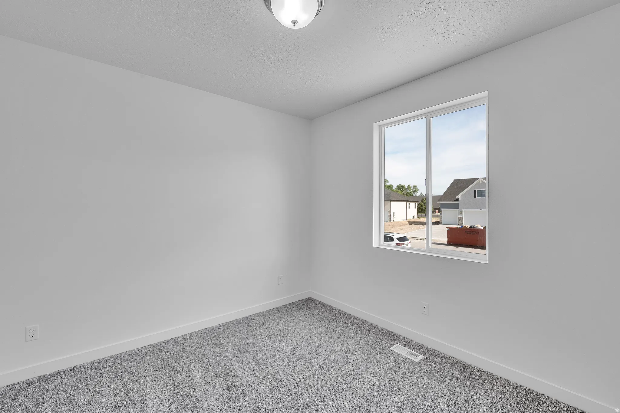 Room featuring a large window, light gray carpet, white walls, white baseboards, and a flush mount ceiling light fixture