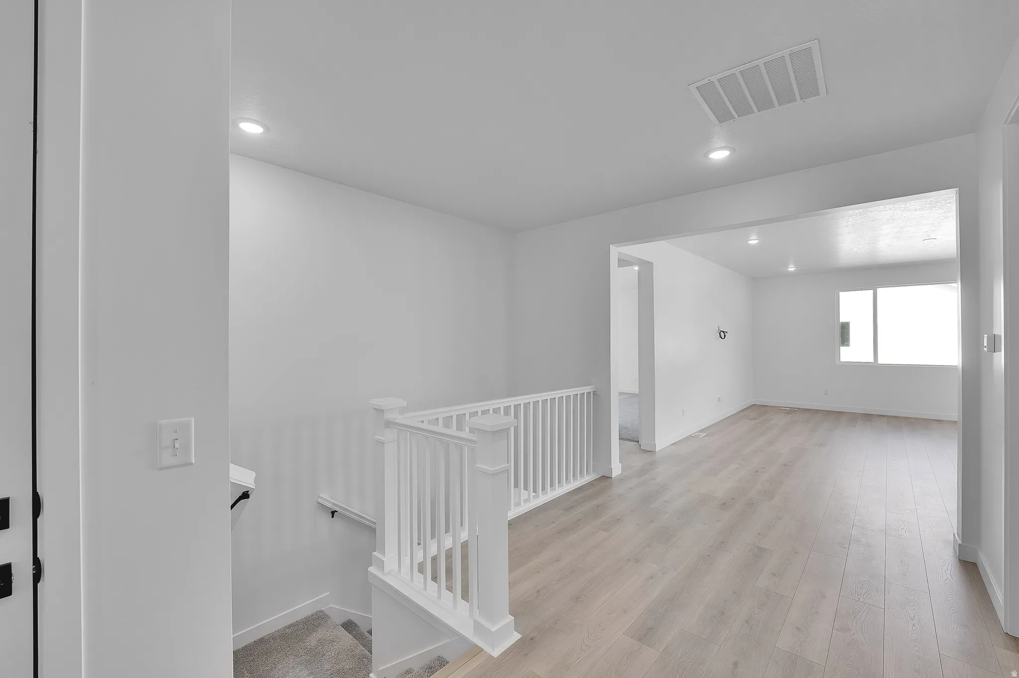 Open concept living area featuring wood-finish flooring, recessed lighting, and a window providing natural illumination