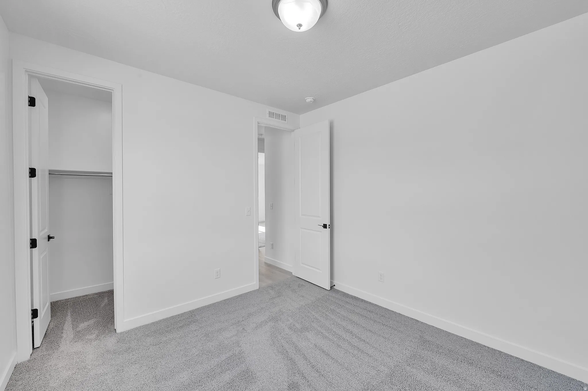 Carpeted room featuring a ceiling-mounted light fixture, white walls, and white trim