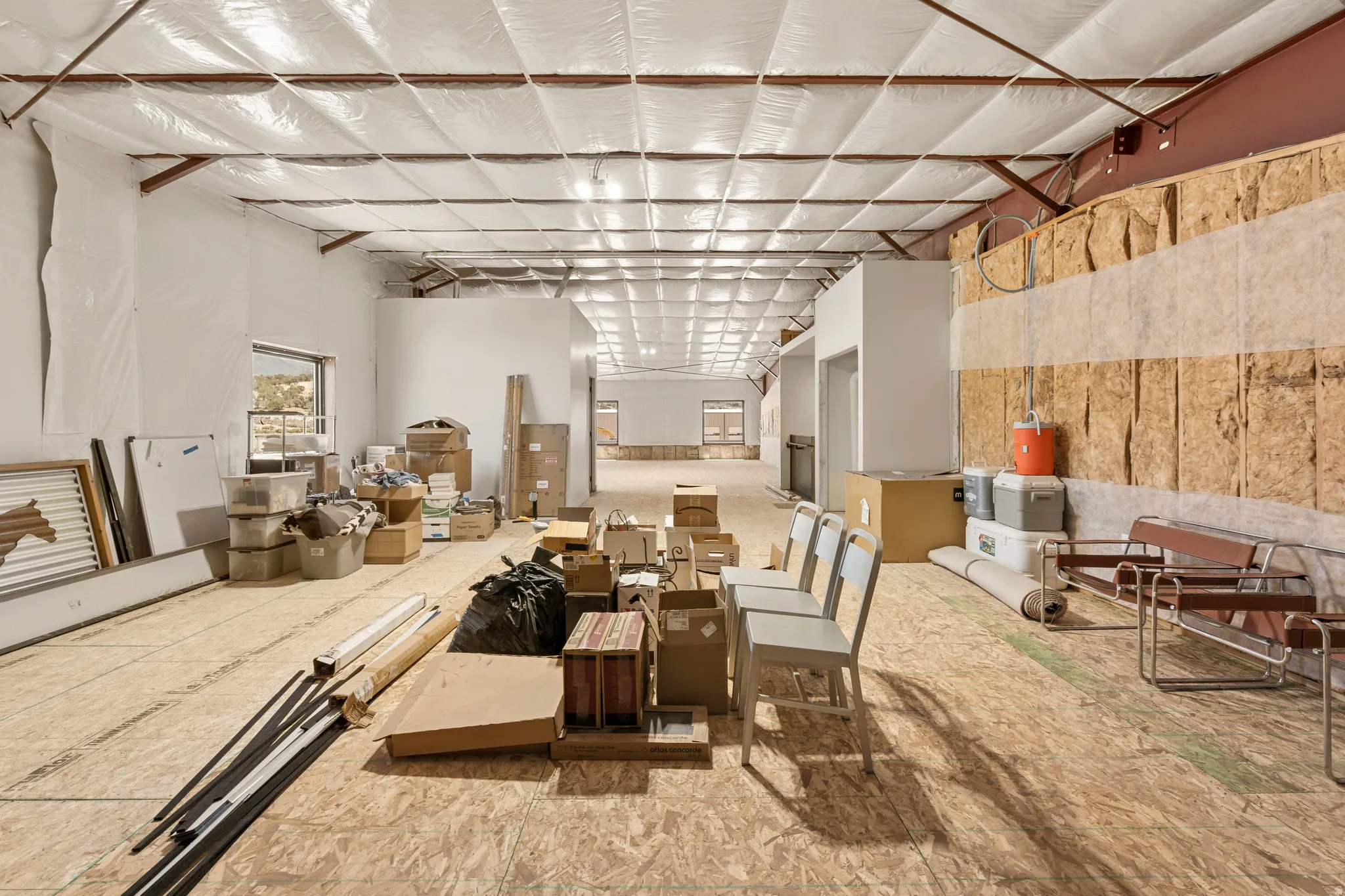 Unfinished interior space featuring exposed wood subflooring, open ceiling with insulation, and rough-in walls
