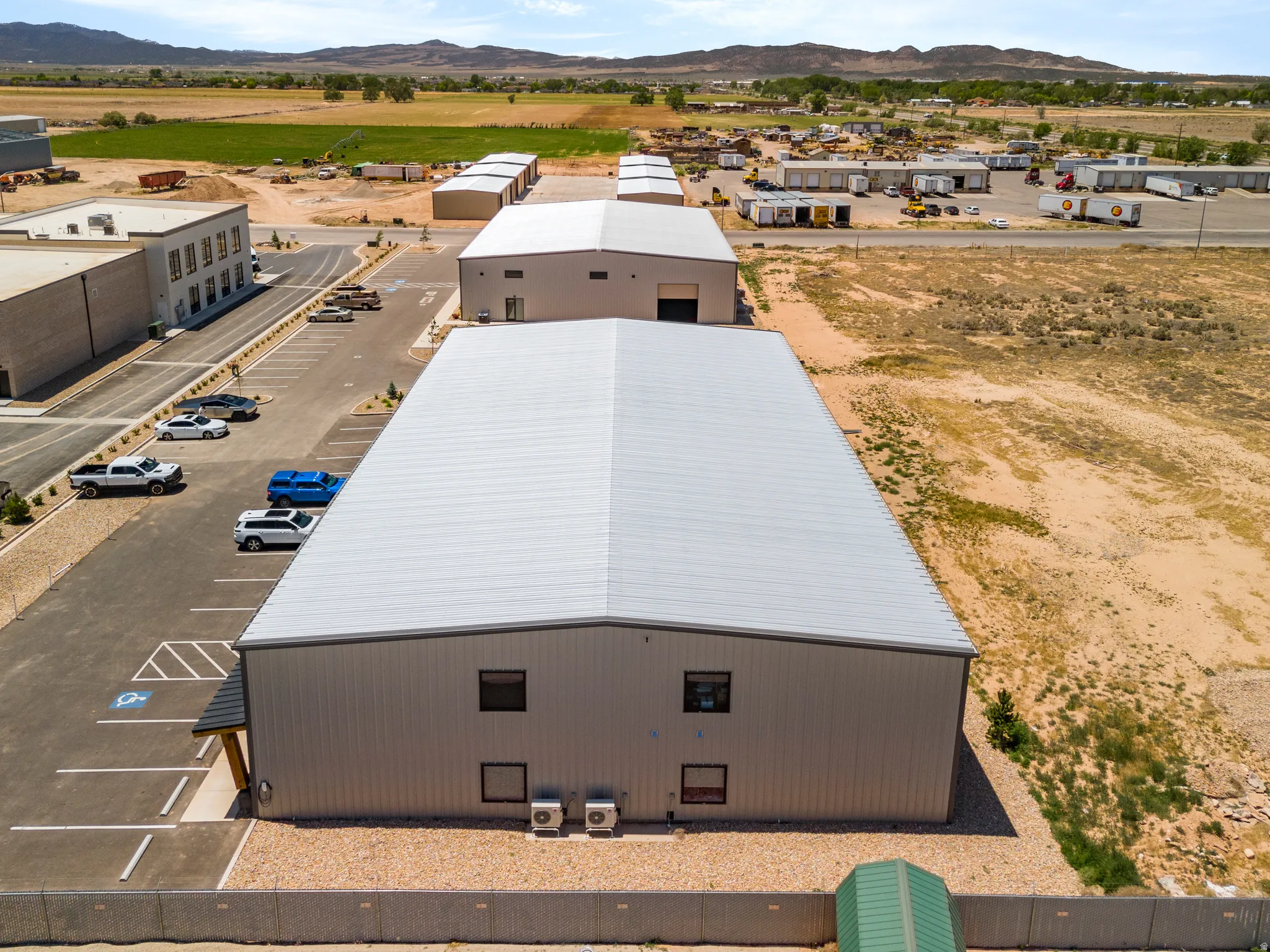 Industrial building featuring a metal roof, corrugated metal siding, multiple window openings, and exterior HVAC units