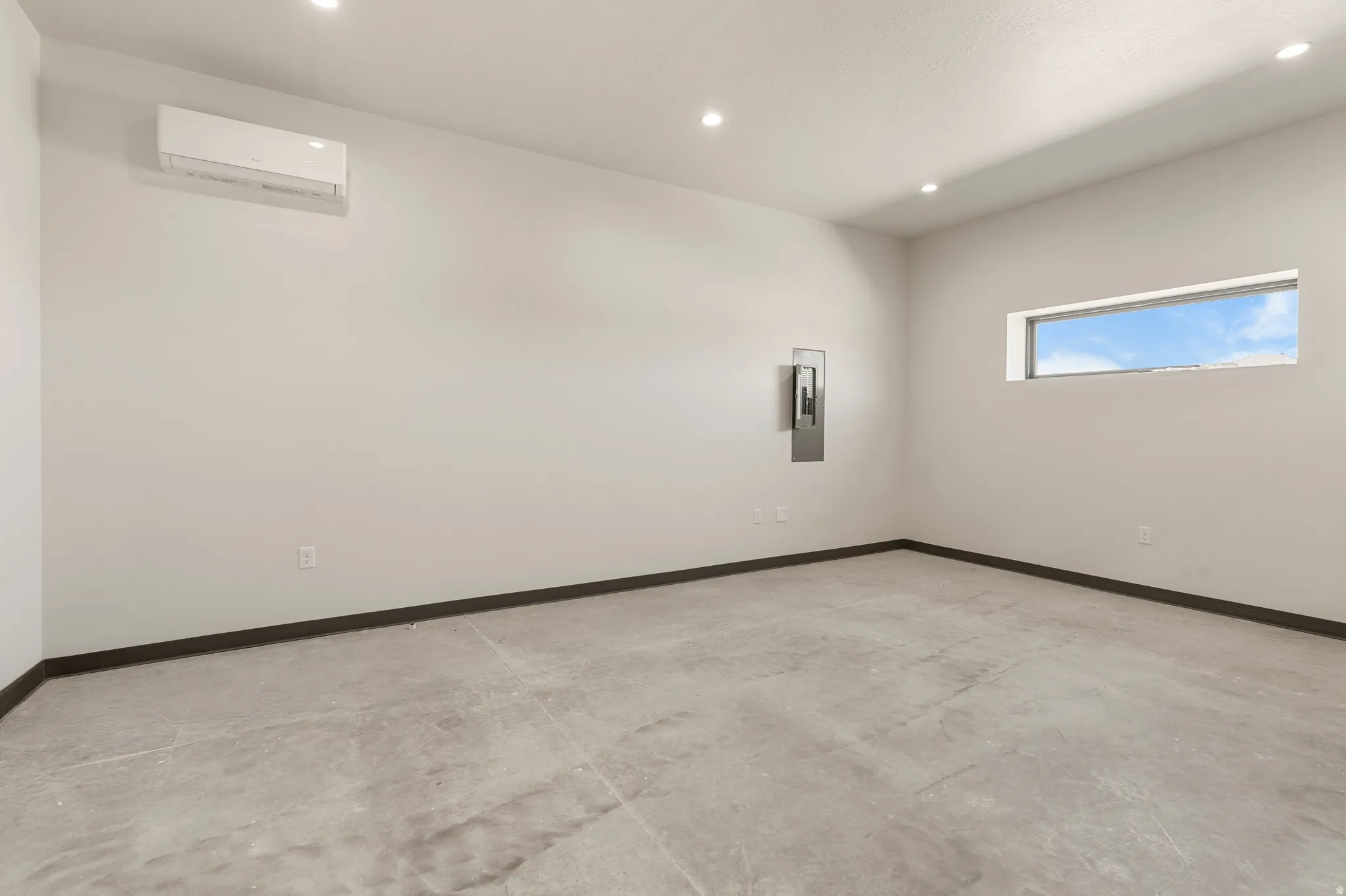 Spacious room featuring light gray walls, dark baseboards, and a polished concrete floor