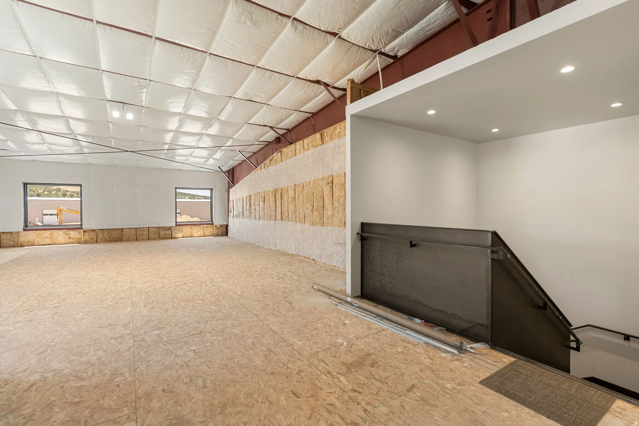 Spacious interior with exposed structural beams, high ceilings, and recessed lighting