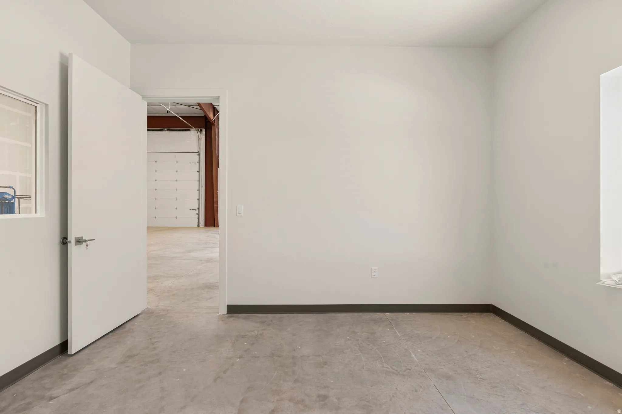 Spacious room featuring concrete flooring and crisp white walls